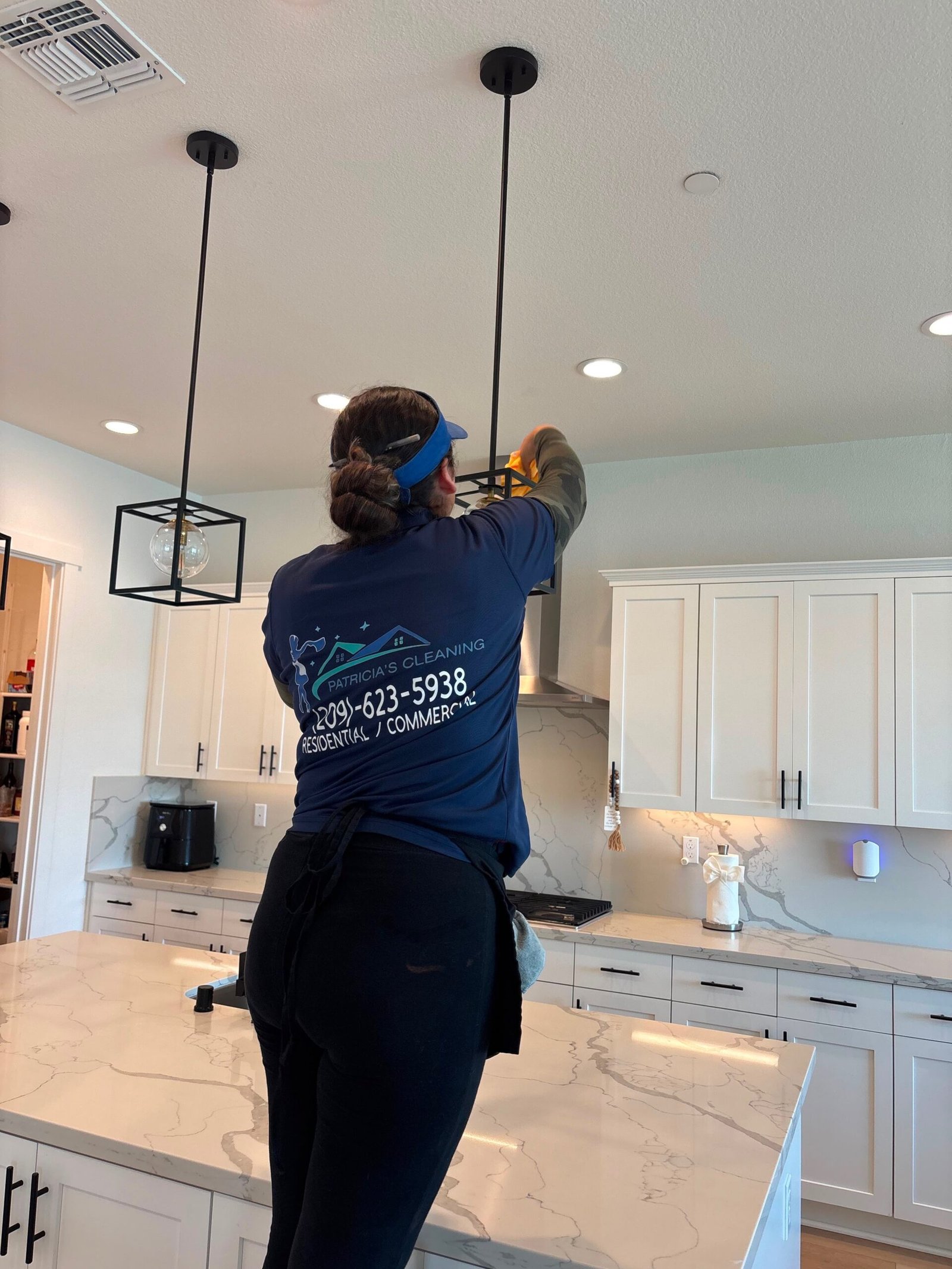Patricia's Cleaning professional cleaning a kitchen light fixture